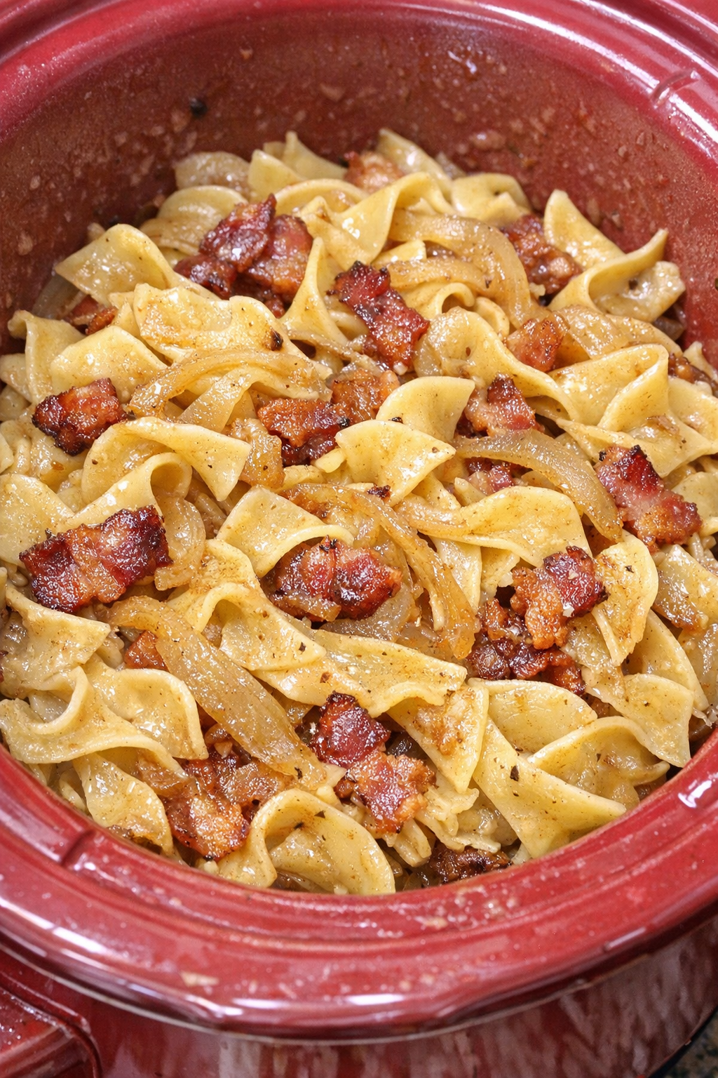 Slow cooker Amish bacon onion noodles in a red slow cooker