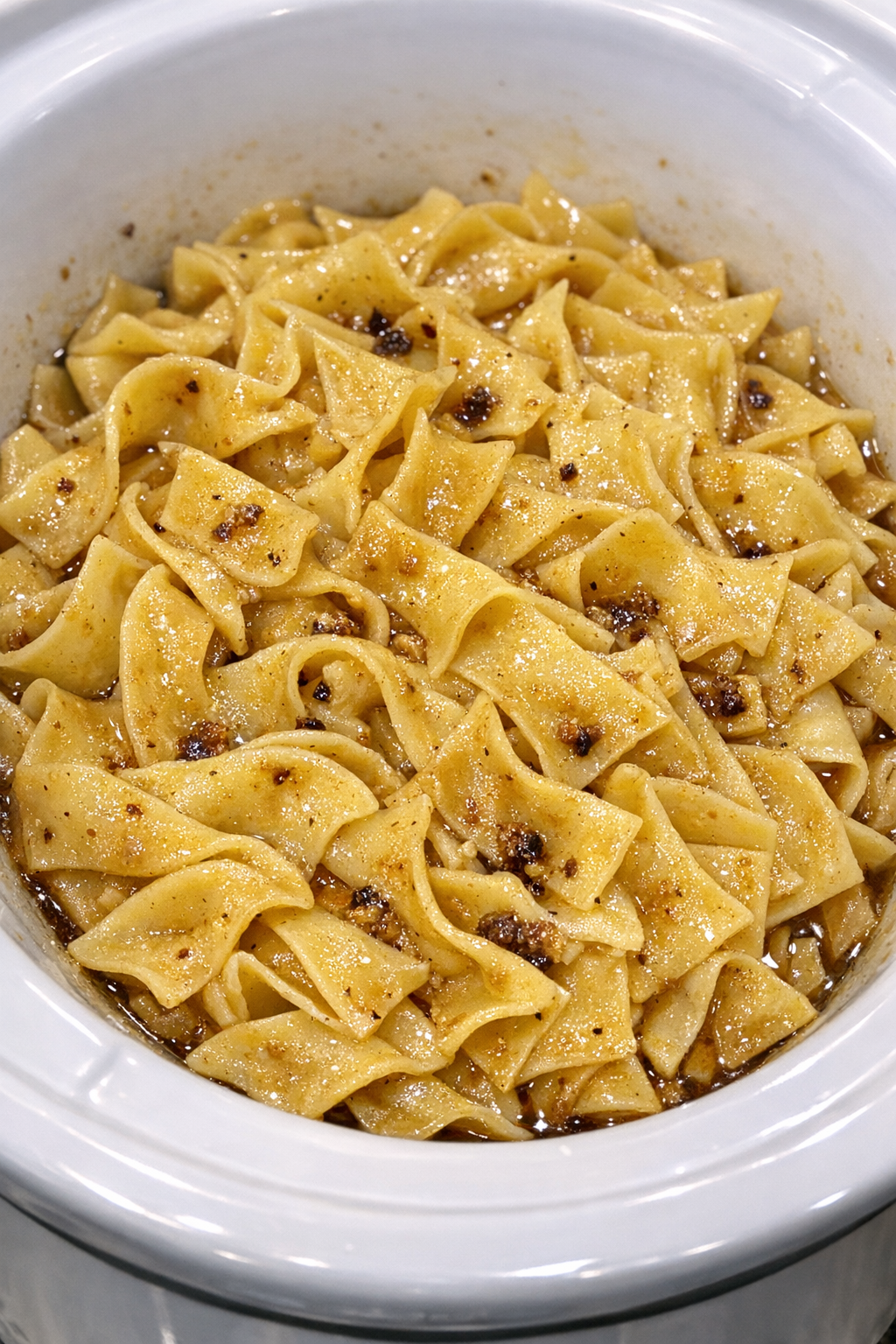 Slow cooker Amish brown butter noodles in a white slow cooker