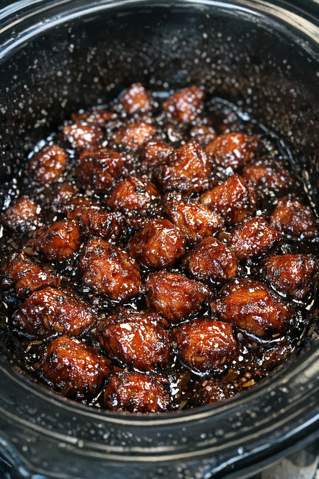 Slow cooker filled with caramelized glazed protein morsels