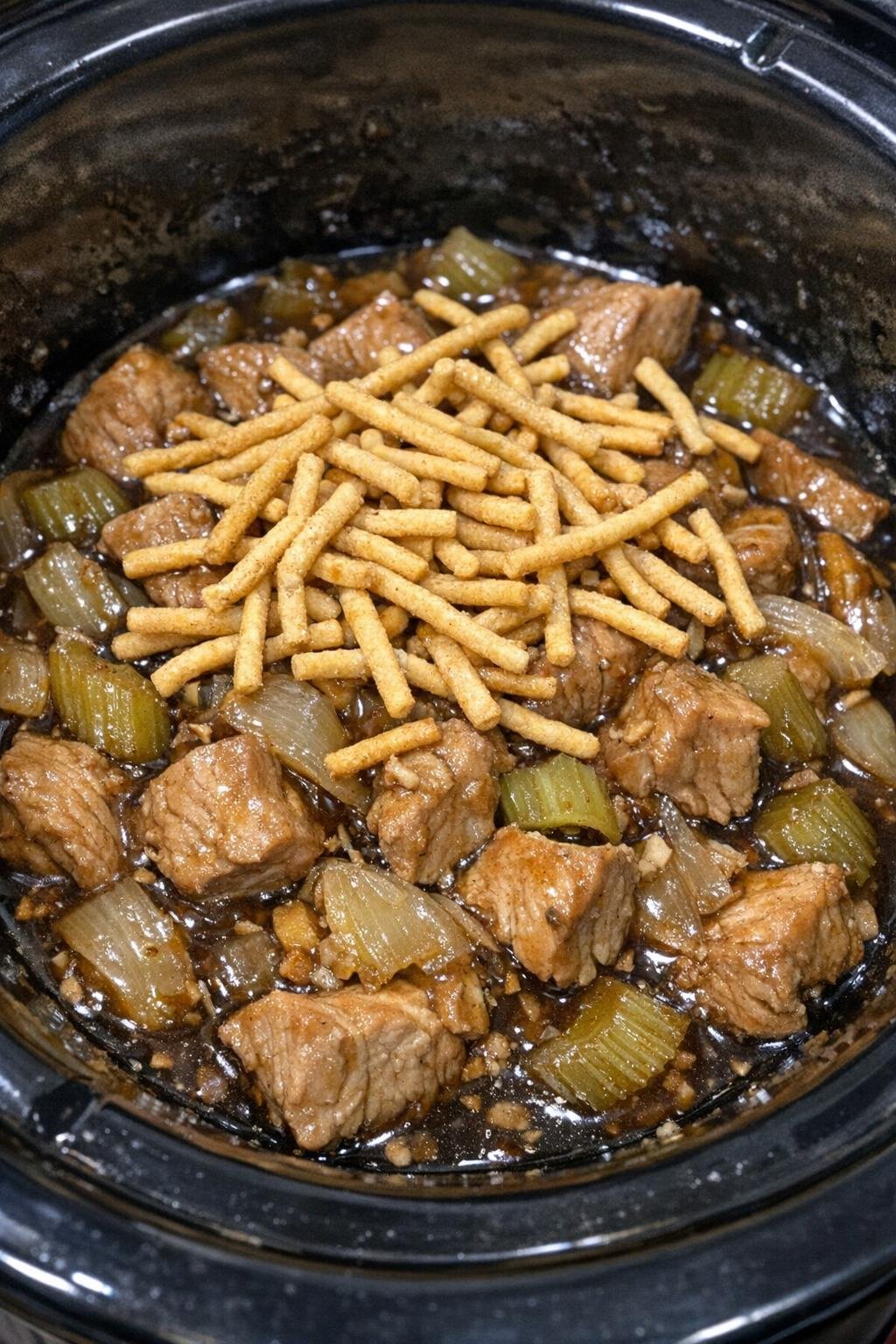 Slow cooker pork chop suey in a black slow cooker crock