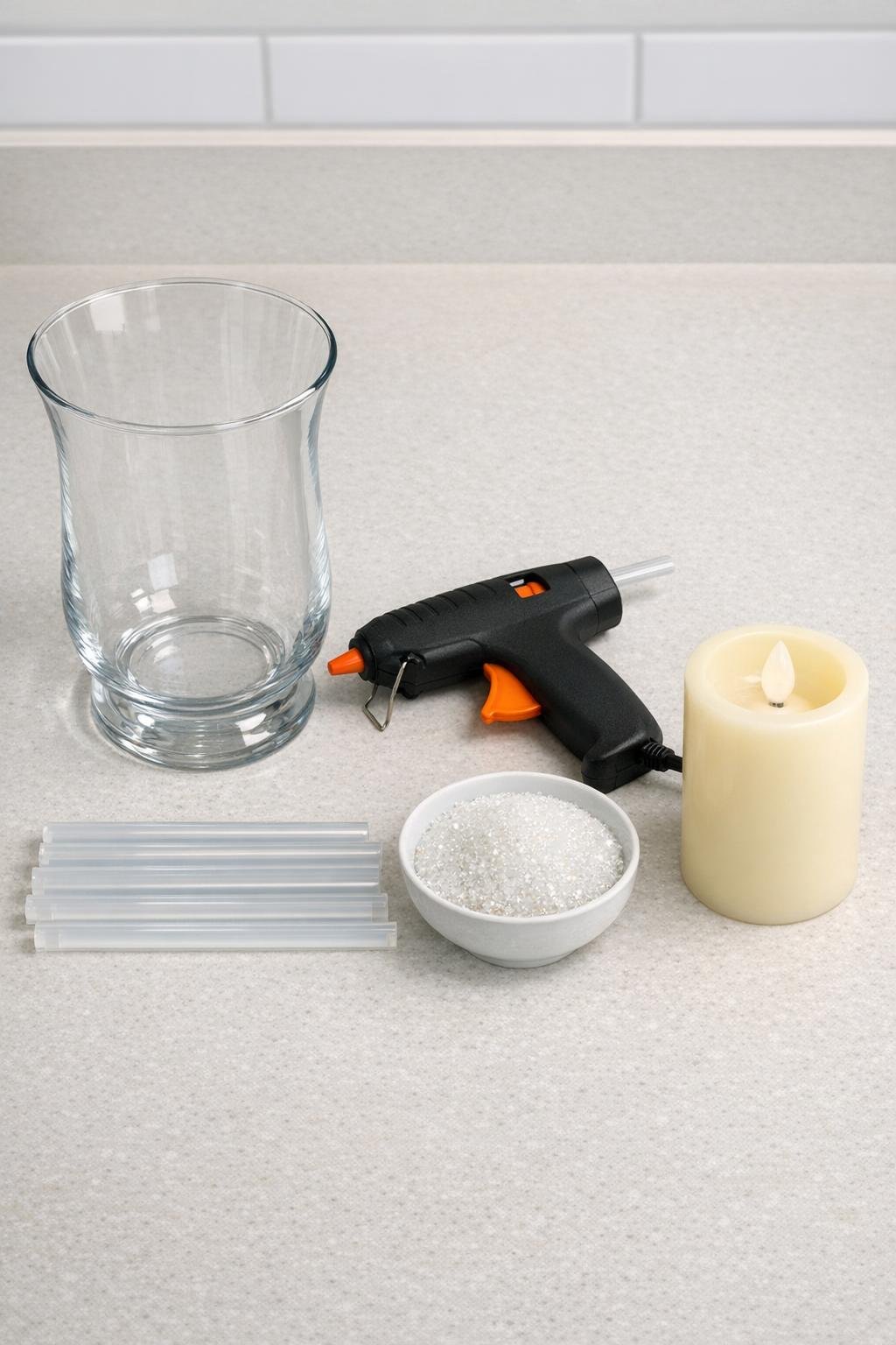Materials for the glass hurricane vase winter luminary laid out on a counter