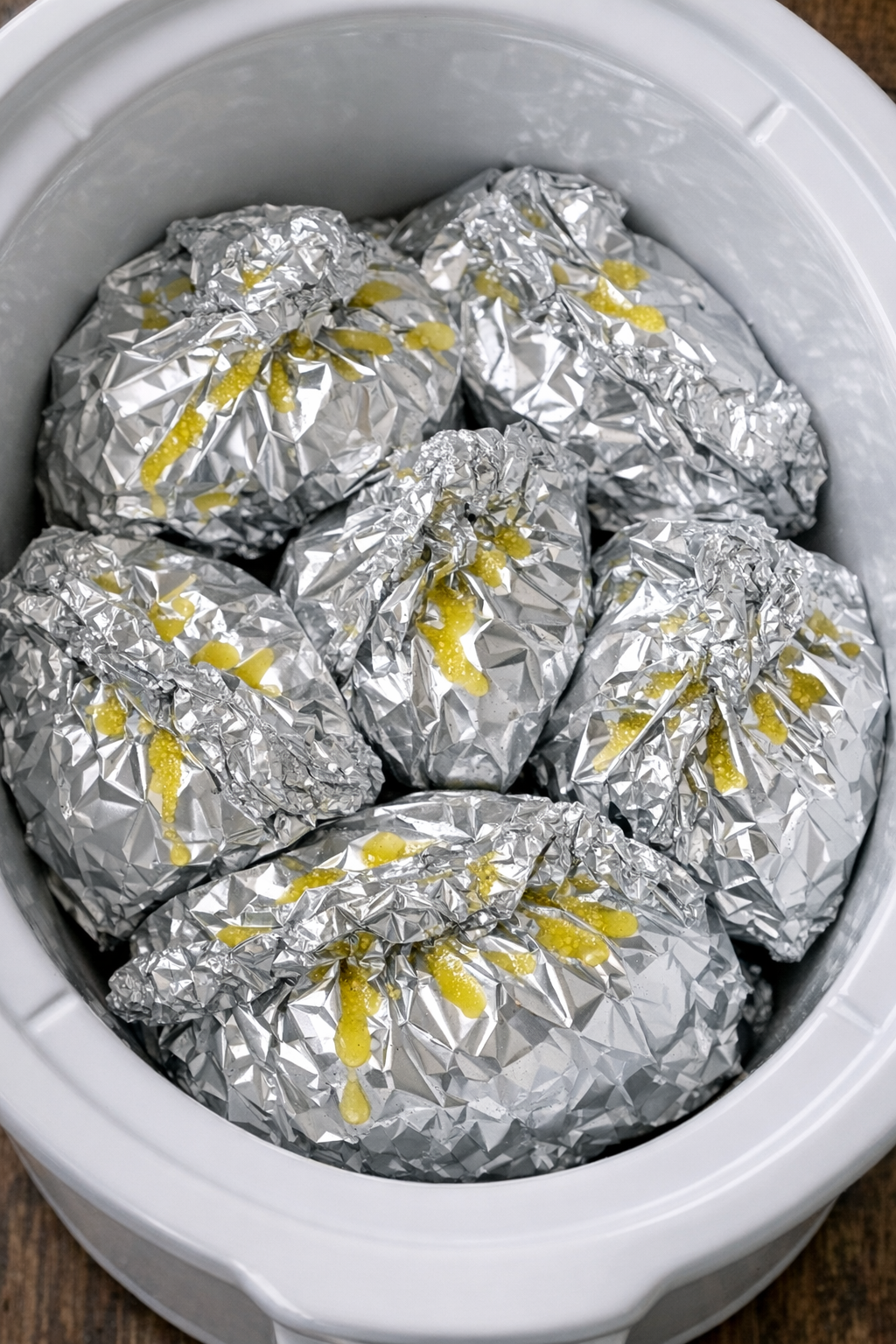 Slow cooker foil pasta packets in a white slow cooker