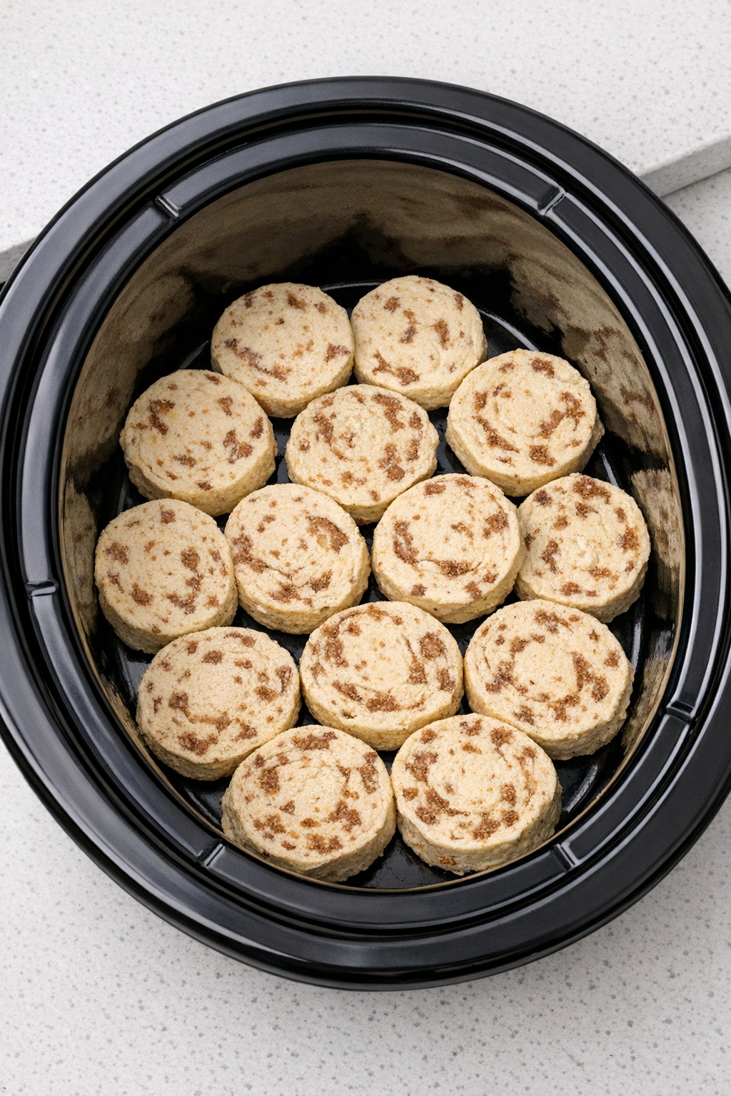 Cinnamon roll dough arranged in the slow cooker