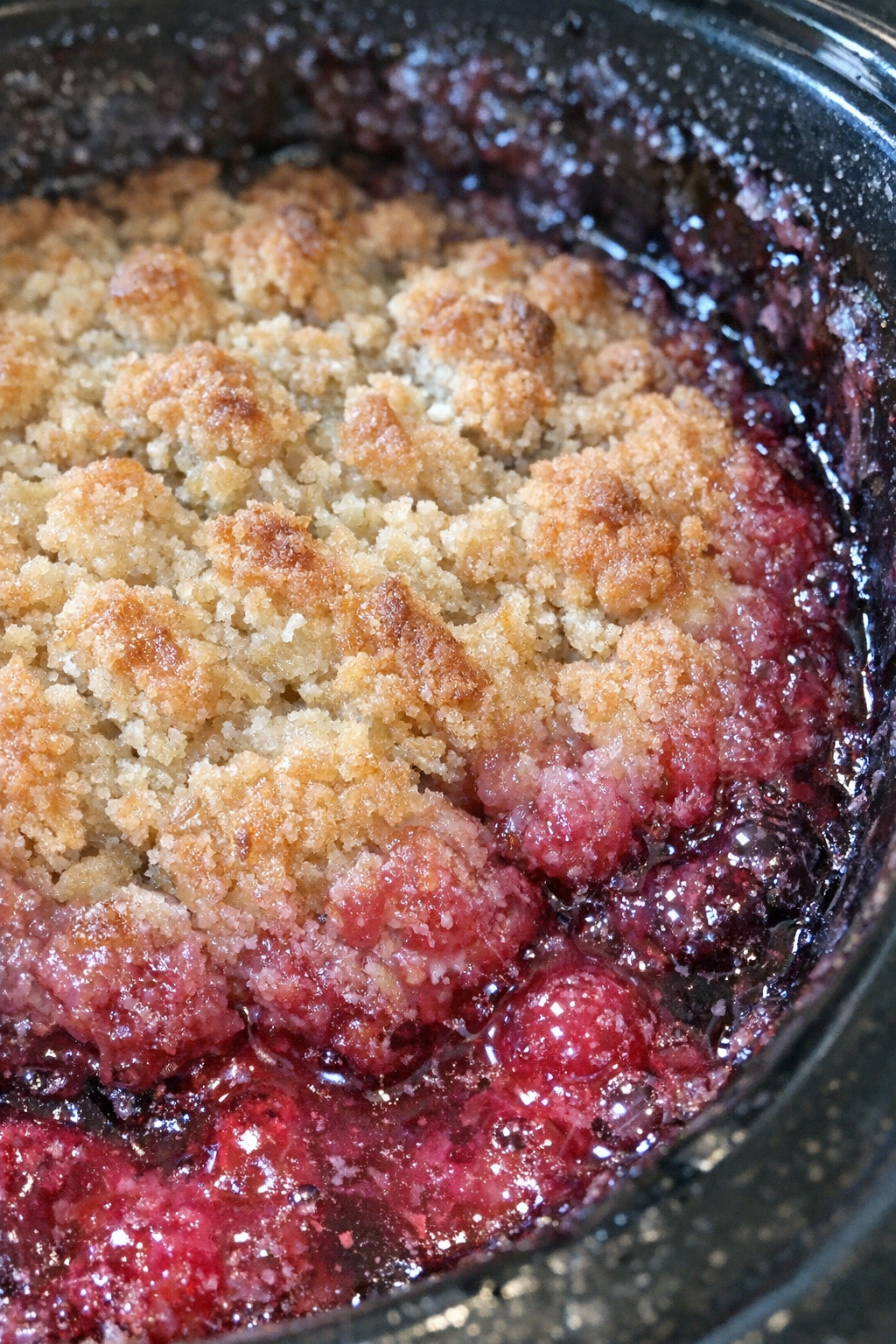 Slow cooker dessert with golden-brown craggy top and molten magenta fruit