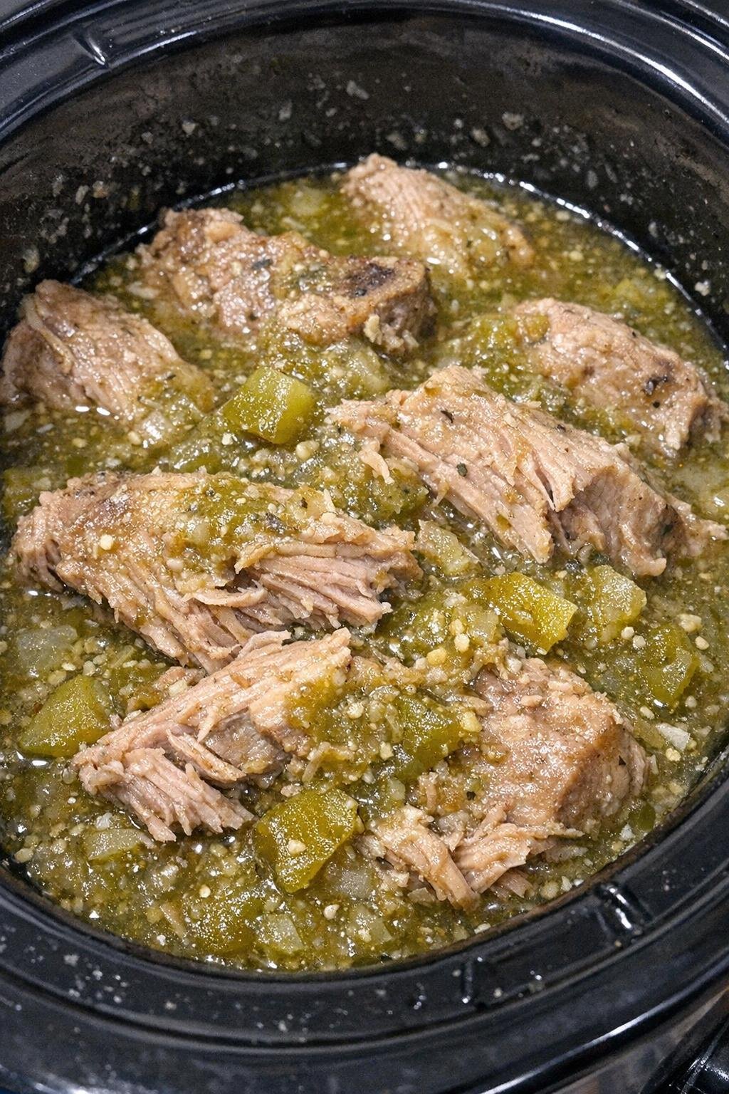 Slow cooker salsa verde pork chops in a black slow cooker