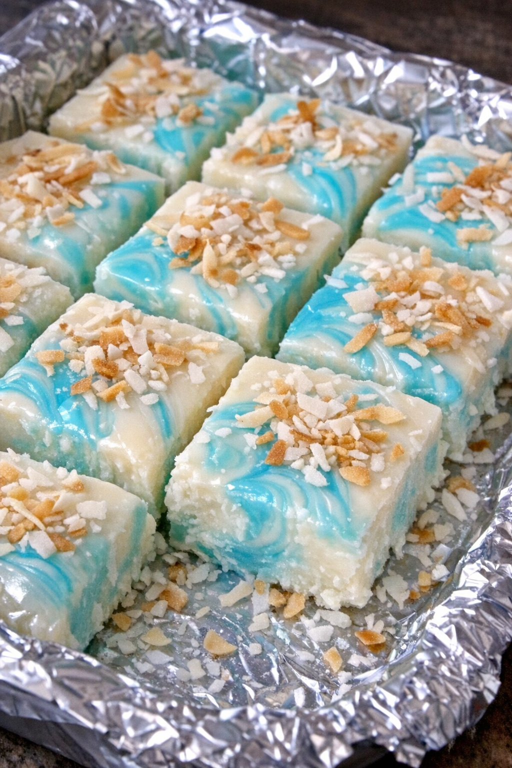 Slow cooker coconut cloud fudge squares in a foil-lined pan