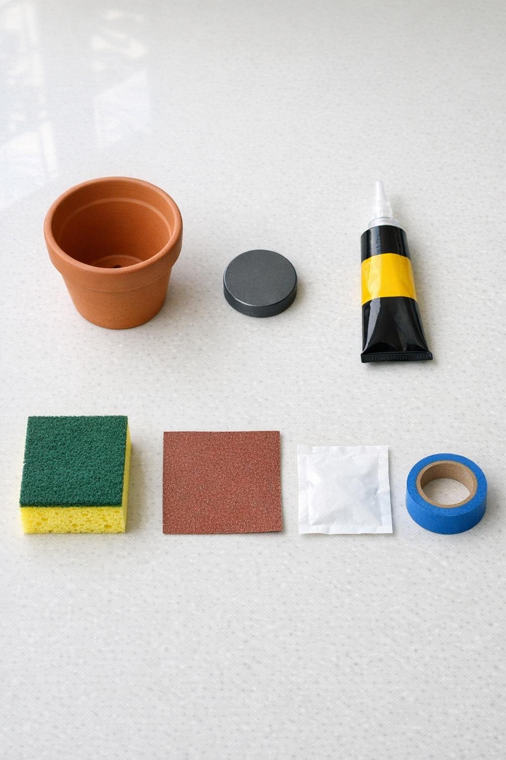 Materials for a magnetic terra cotta pot sponge holder laid out on a counter