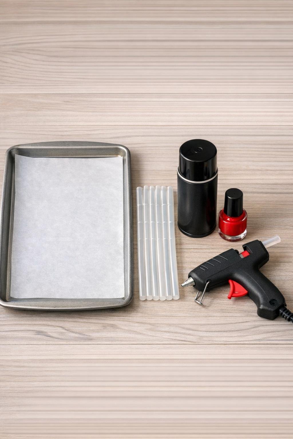 Materials for making hot glue spiders laid out on a baking sheet and table