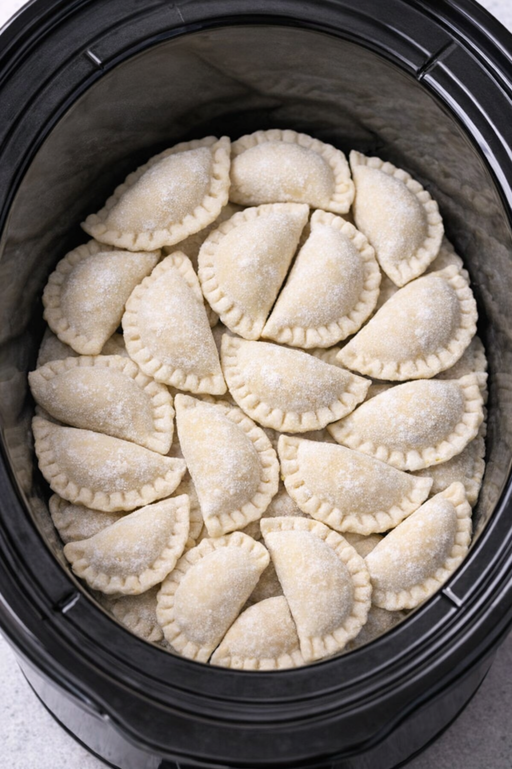 Frozen pierogi layered inside a slow cooker