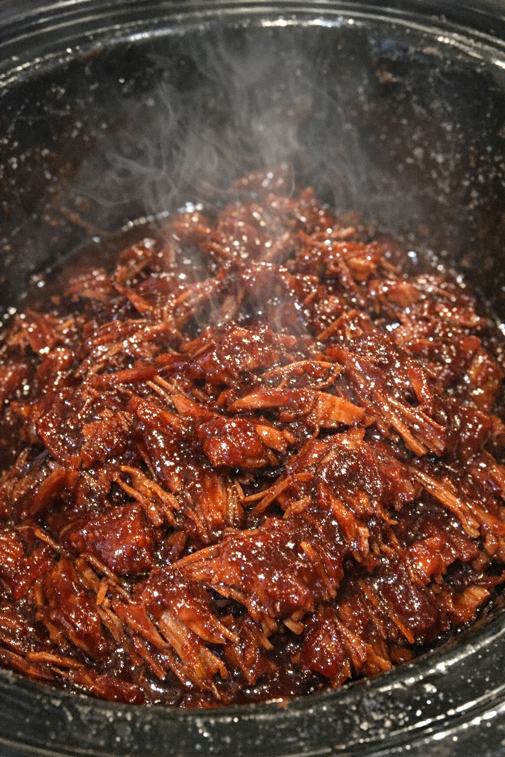 Succulent shredded protein in ruby glaze inside a slow cooker