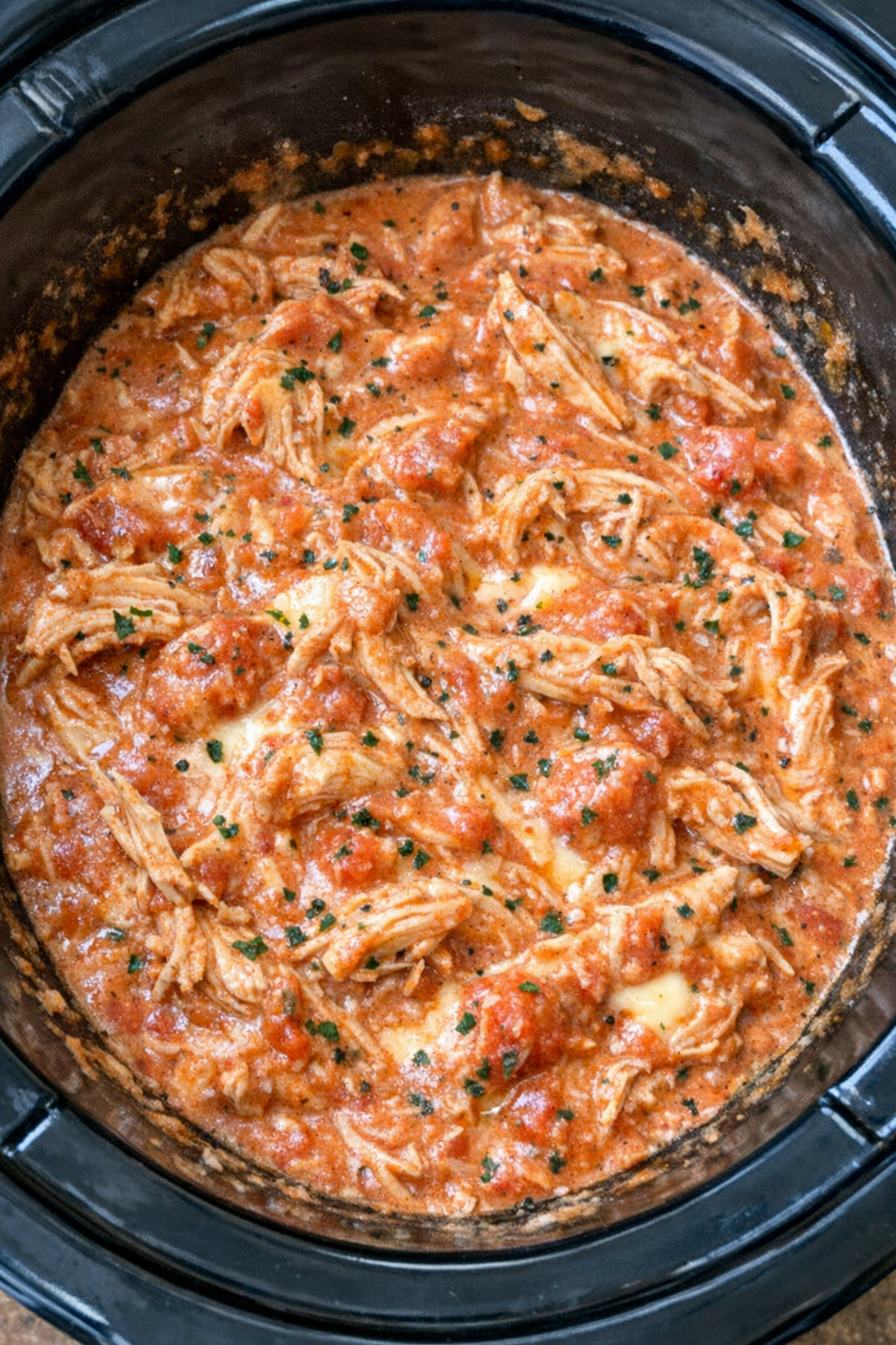 Slow cooker creamy marinara chicken in a black slow cooker