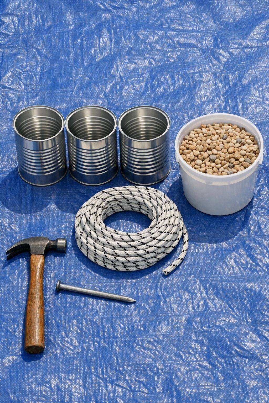 Materials for coffee can garden bed cover weights laid out on a tarp