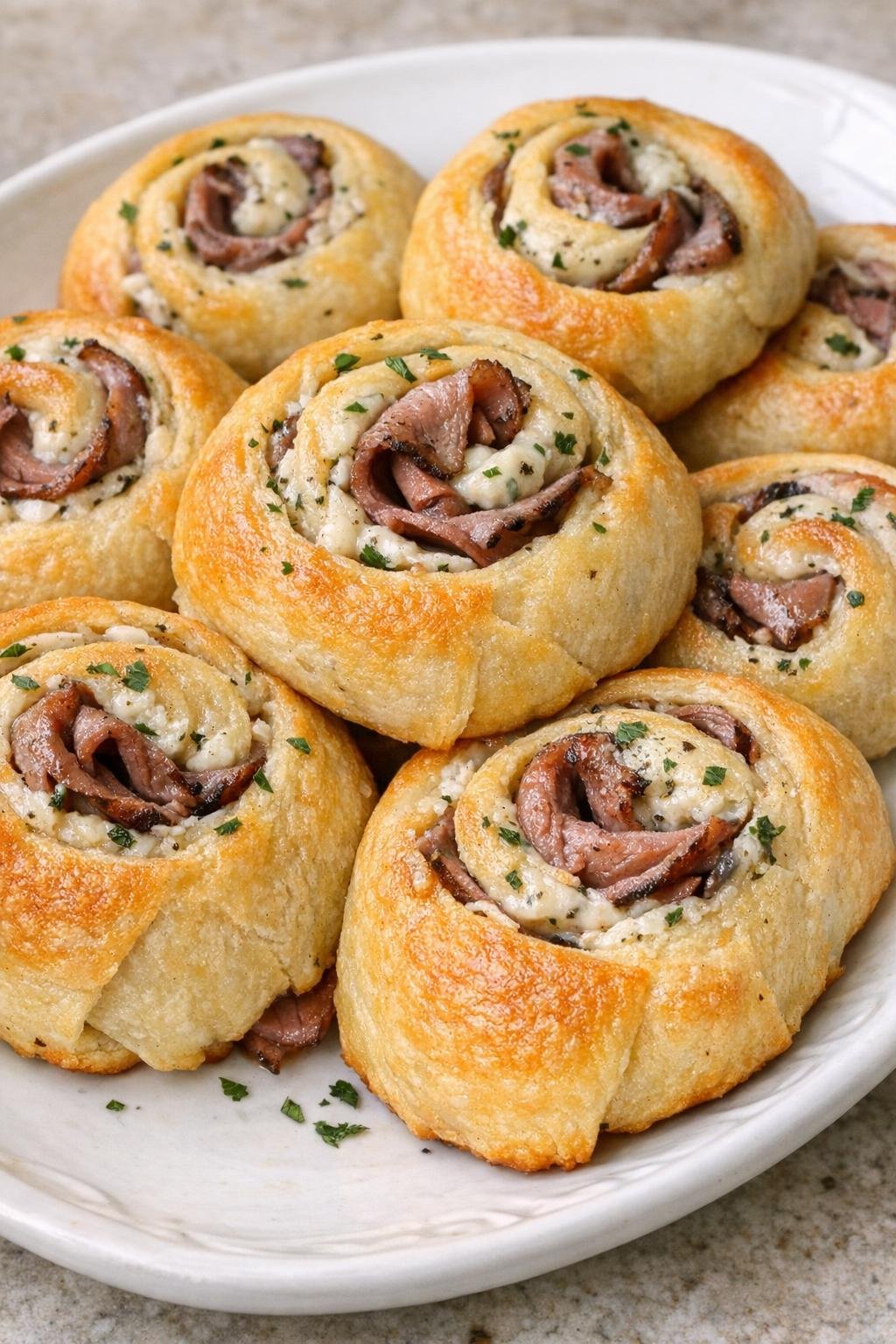 Golden brown roast beef crescent swirls on a white platter