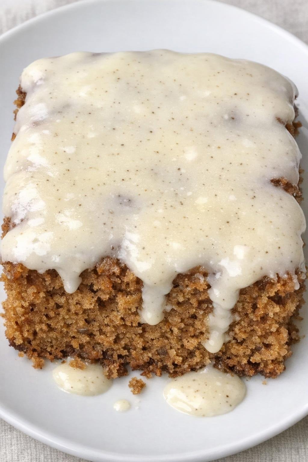 Kruidencake met vanilleglazuur op een wit bord.