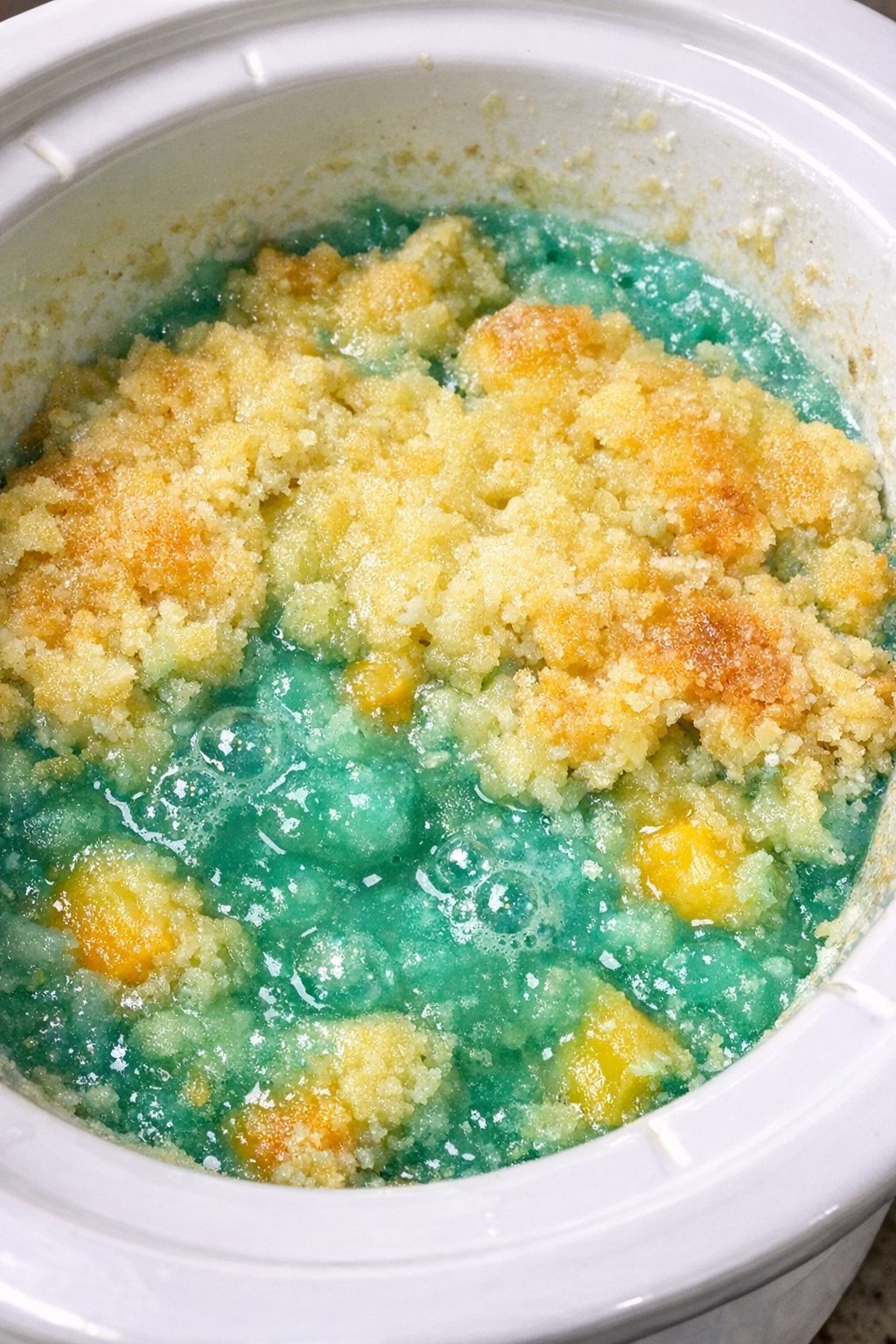 Slow cooker Baja Blast dump cake in a white slow cooker