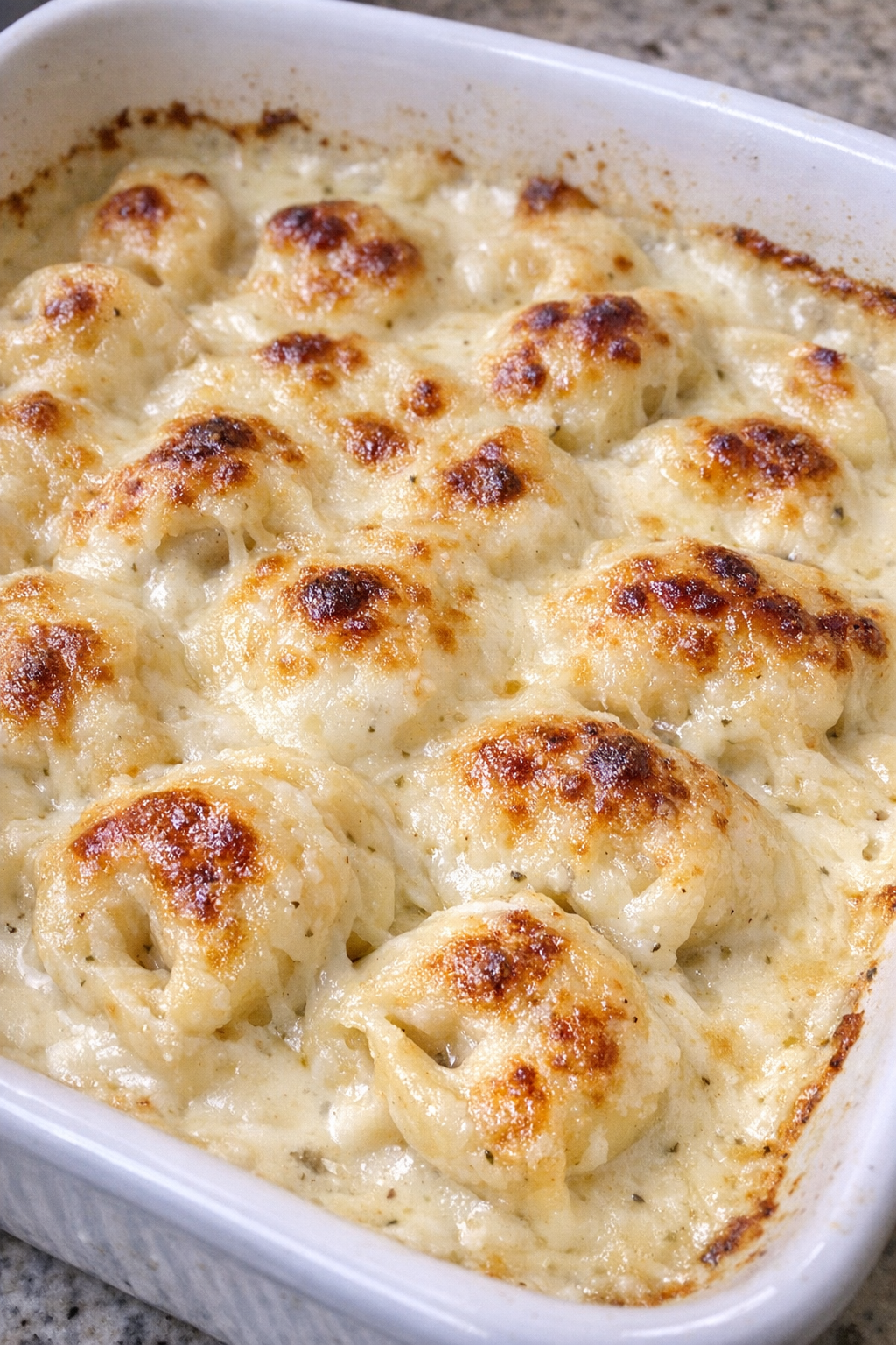 Baked alfredo tortellini in a white casserole dish
