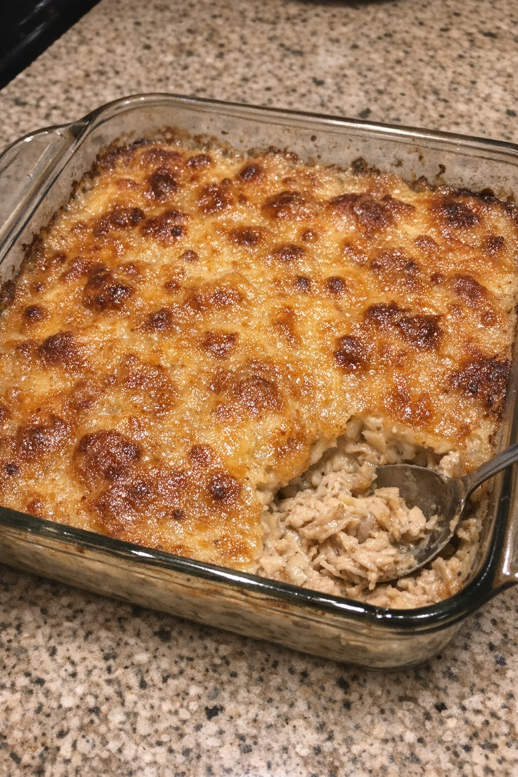Bubbly golden-crusted casserole in a square glass baking dish