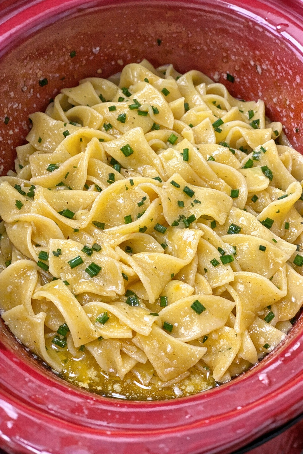 Slow cooker Amish chive butter noodles in a red slow cooker