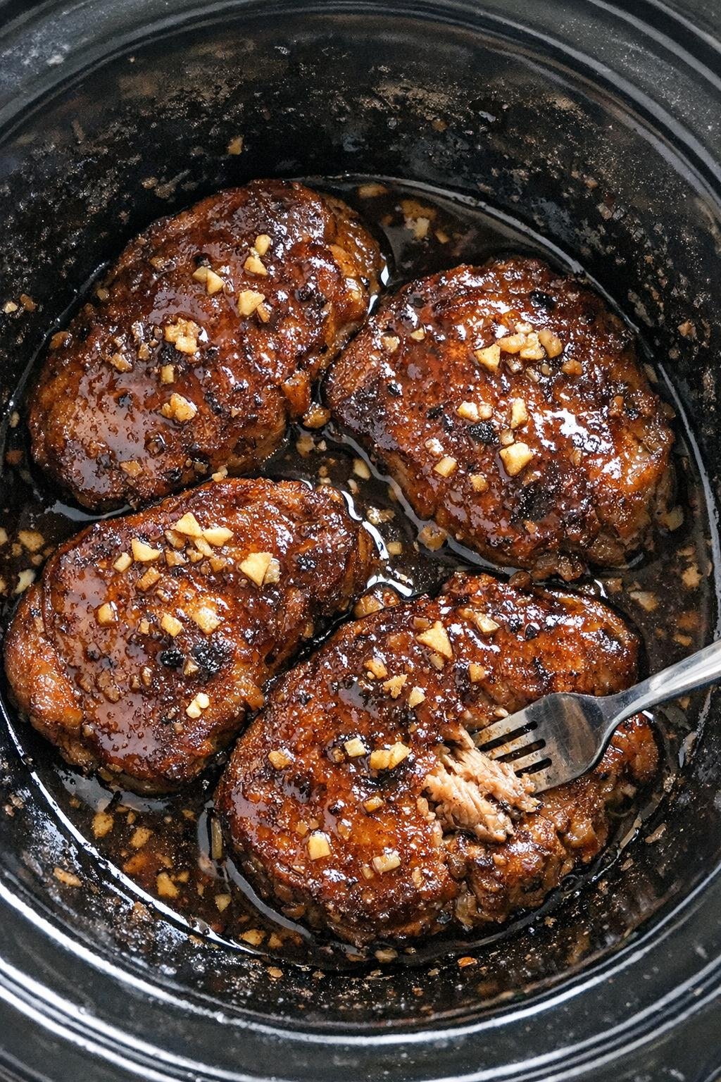 Slow cooker soy ginger pork chops in a black slow cooker