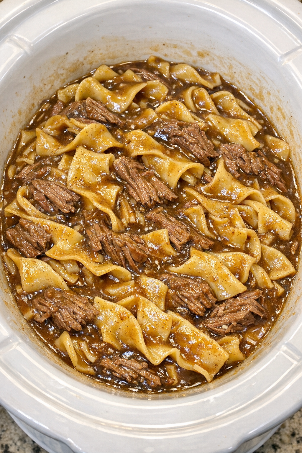 Slow cooker Amish beef gravy noodles in a white slow cooker