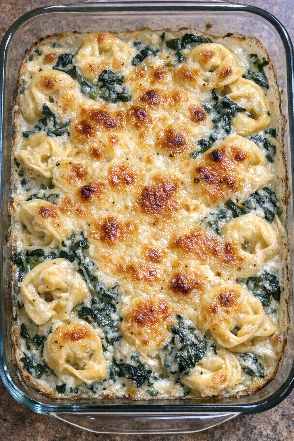 Creamy spinach tortellini baked until golden in a glass dish