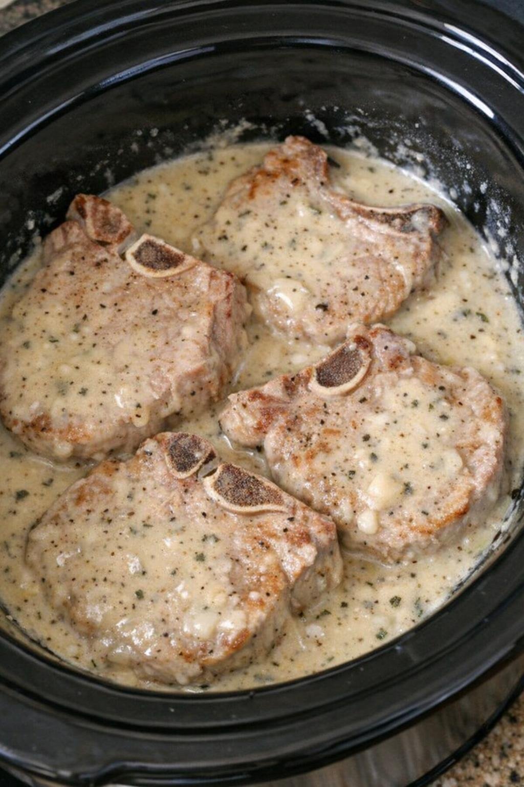 Thick-cut bone-in pork chops cooking in gravy