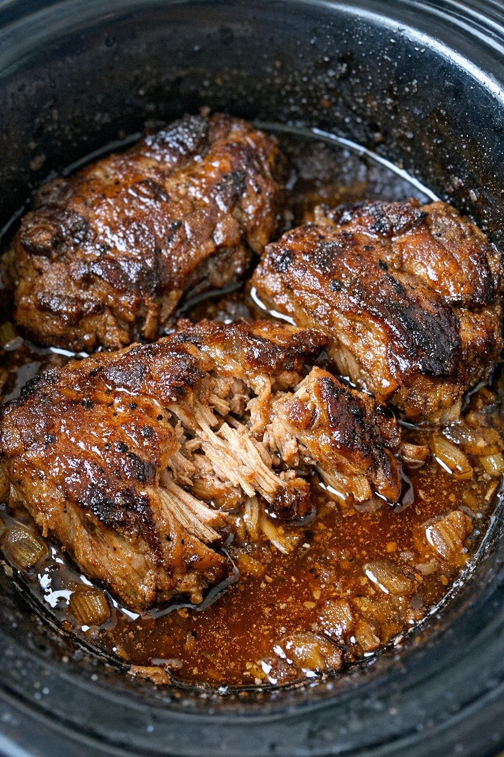 Slow cooker beer braised pork chops in a black slow cooker