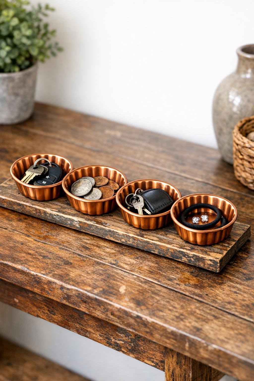 Finished copper muffin tin catch-all on a distressed wooden tray in an entryway