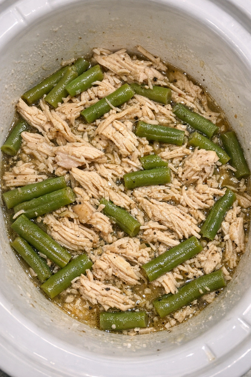 Slow cooker Amish chicken and green beans in a white slow cooker