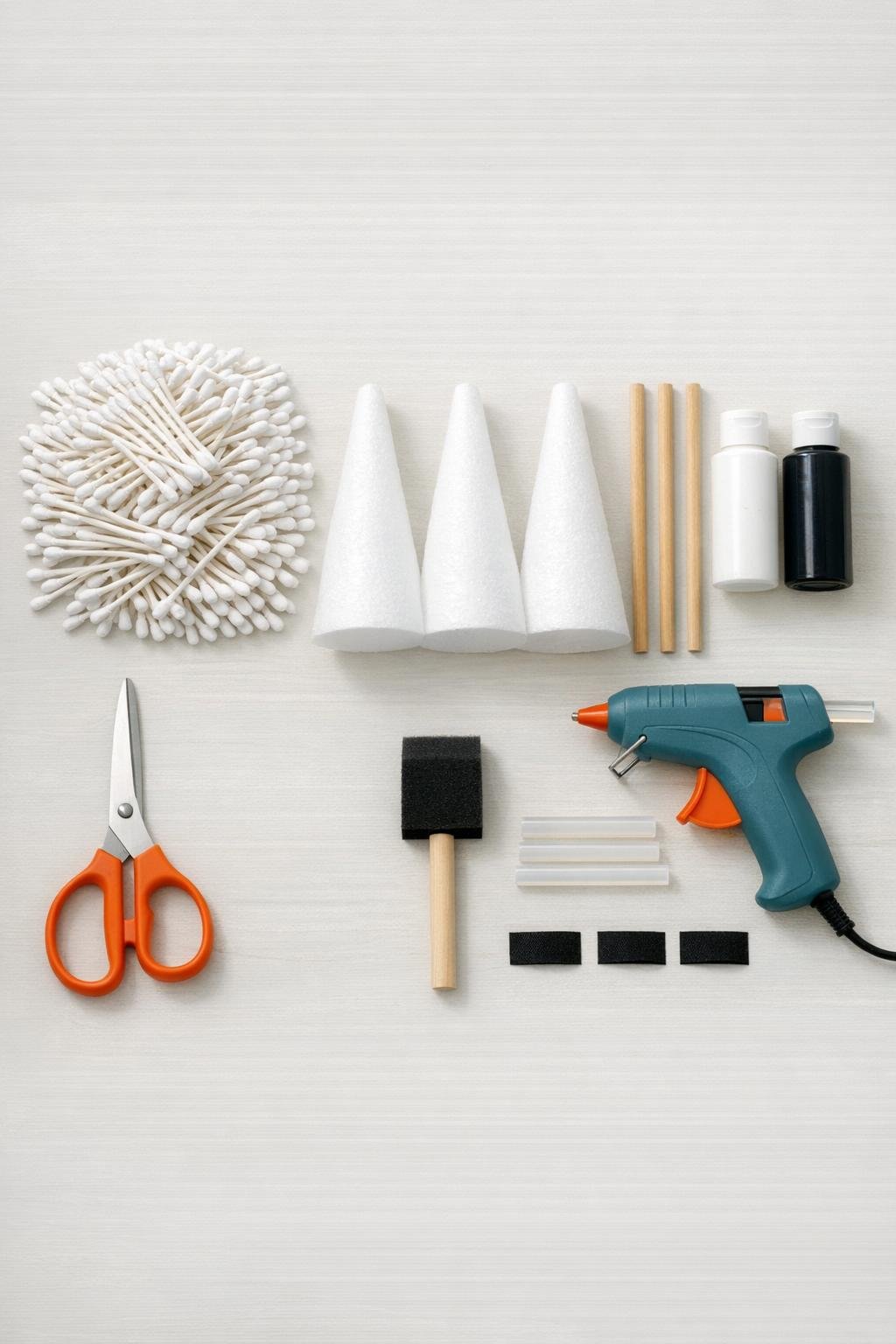 Cotton swabs, foam cones, wooden dowels, paint, ribbon, and glue supplies laid out for the ghost stake project
