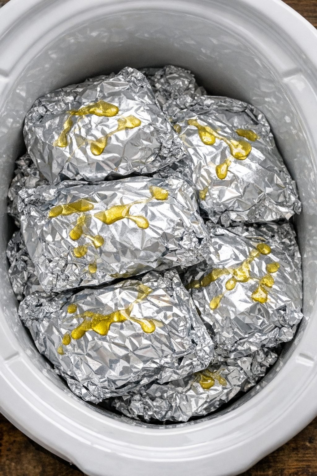 Slow cooker roasted red pepper chicken foil packets in a white slow cooker