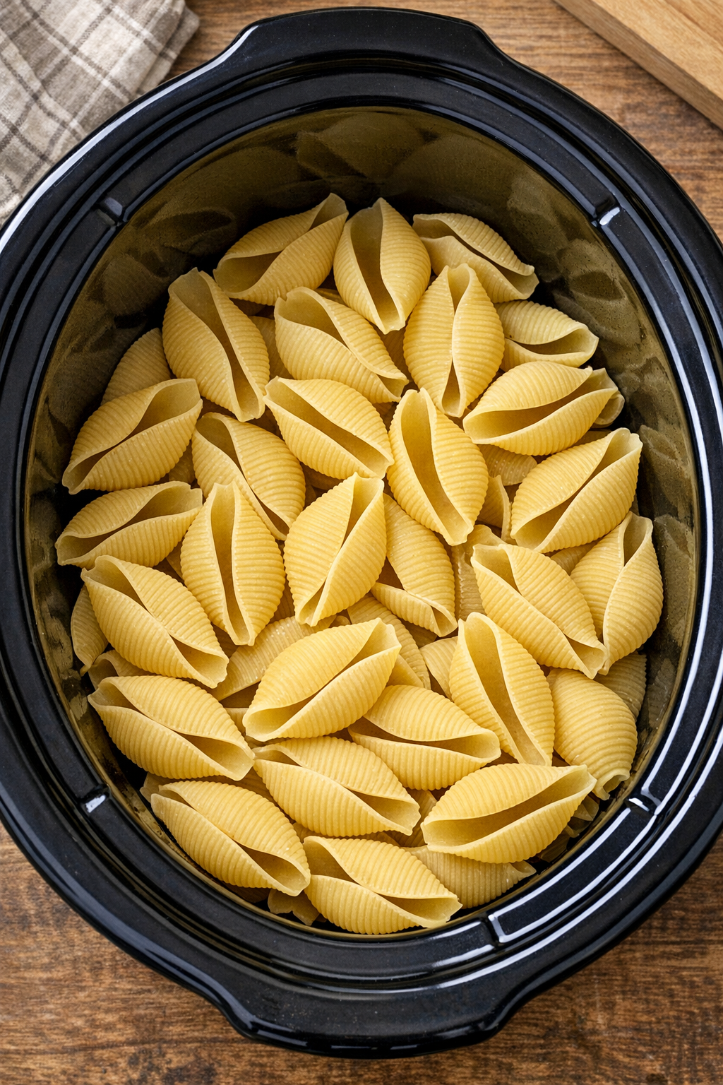 Raw jumbo shells layered in the slow cooker