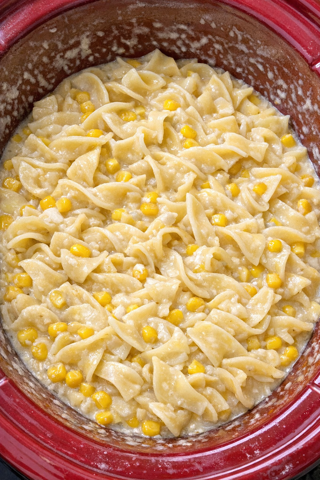 Slow cooker Amish sweet corn cream noodles in a red slow cooker