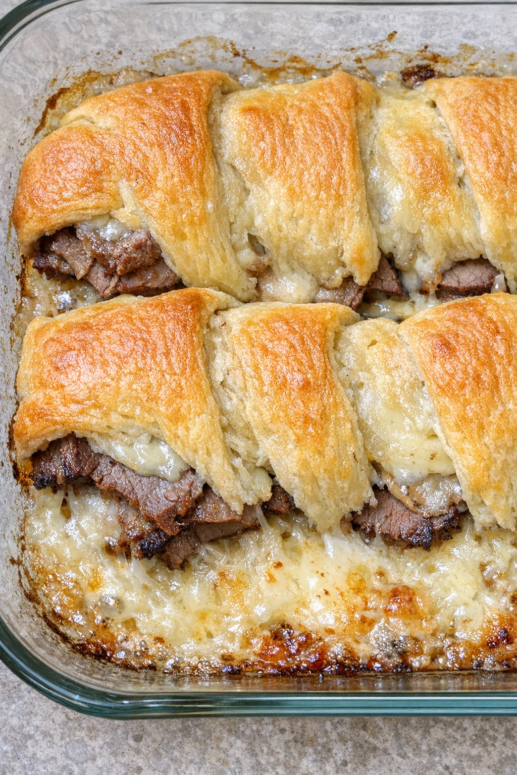 Oven baked beef crescent slices in a glass casserole dish
