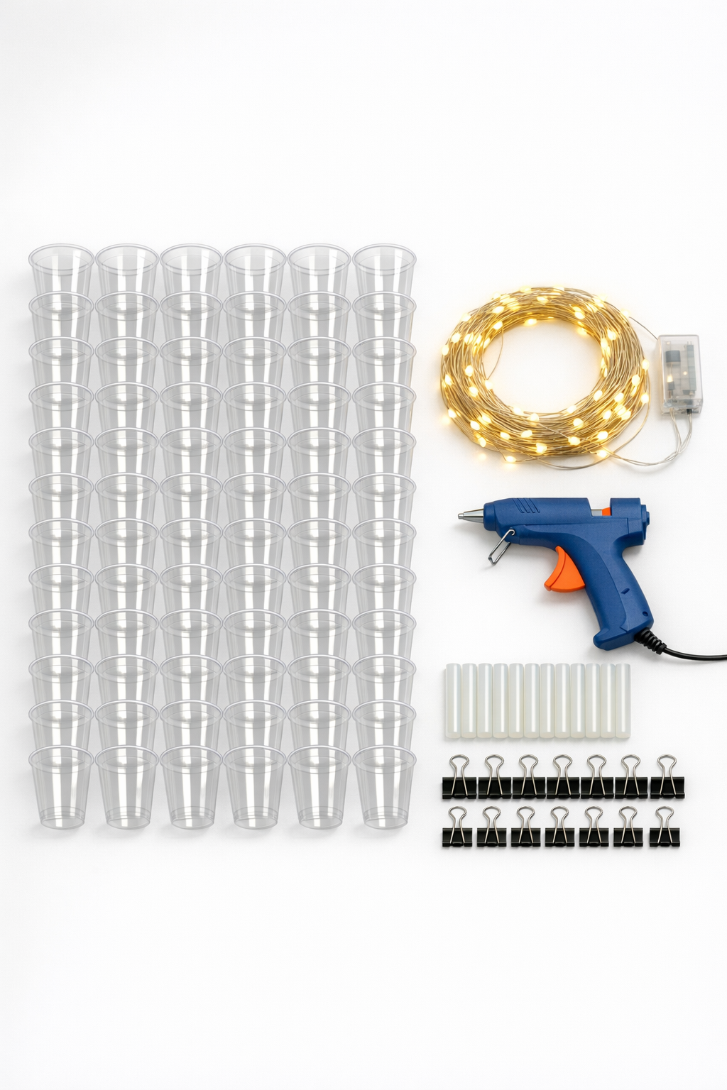 Clear plastic cups, glue, and warm white LED string lights laid out for the project