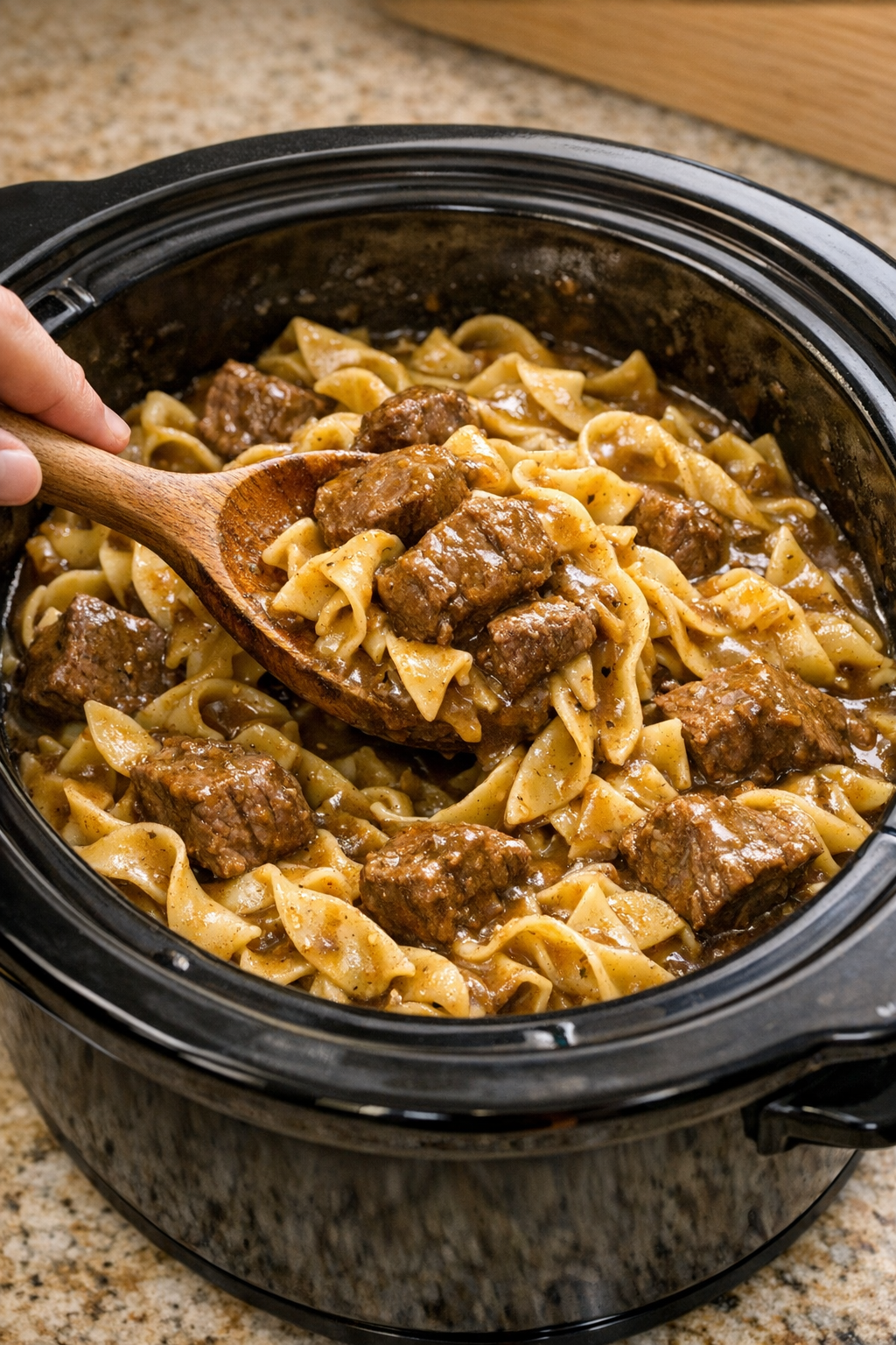 Cooked beef and noodles being stirred in the slow cooker