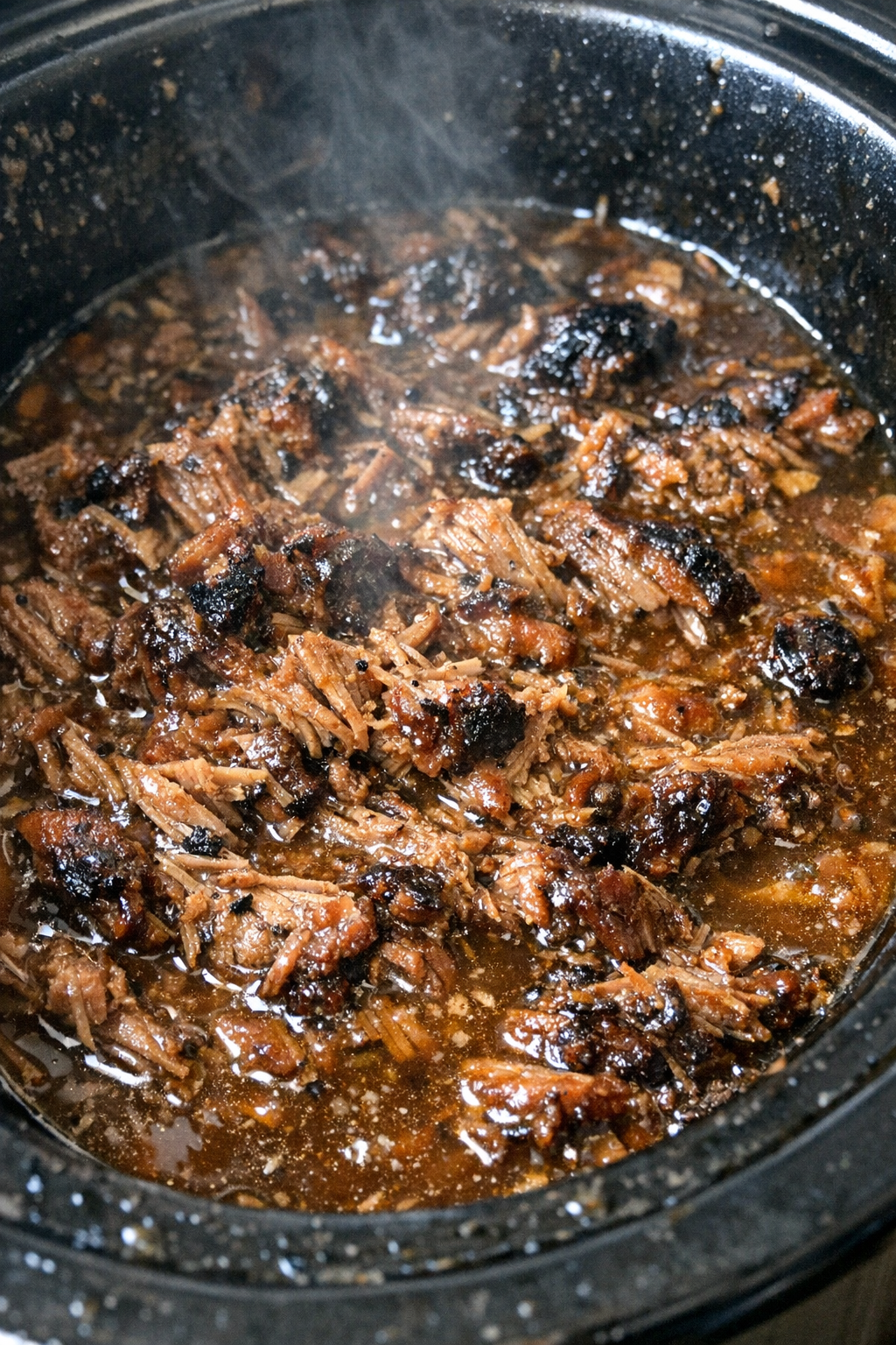 Shredded pork brisket in savory gravy in a slow cooker