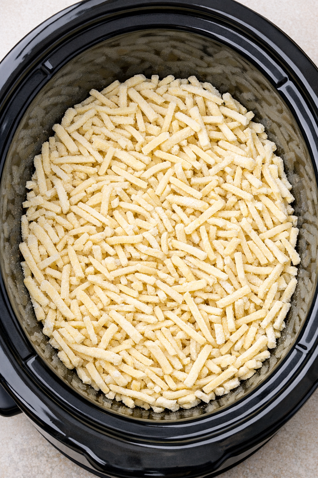 Frozen shoestring potatoes spread in a slow cooker