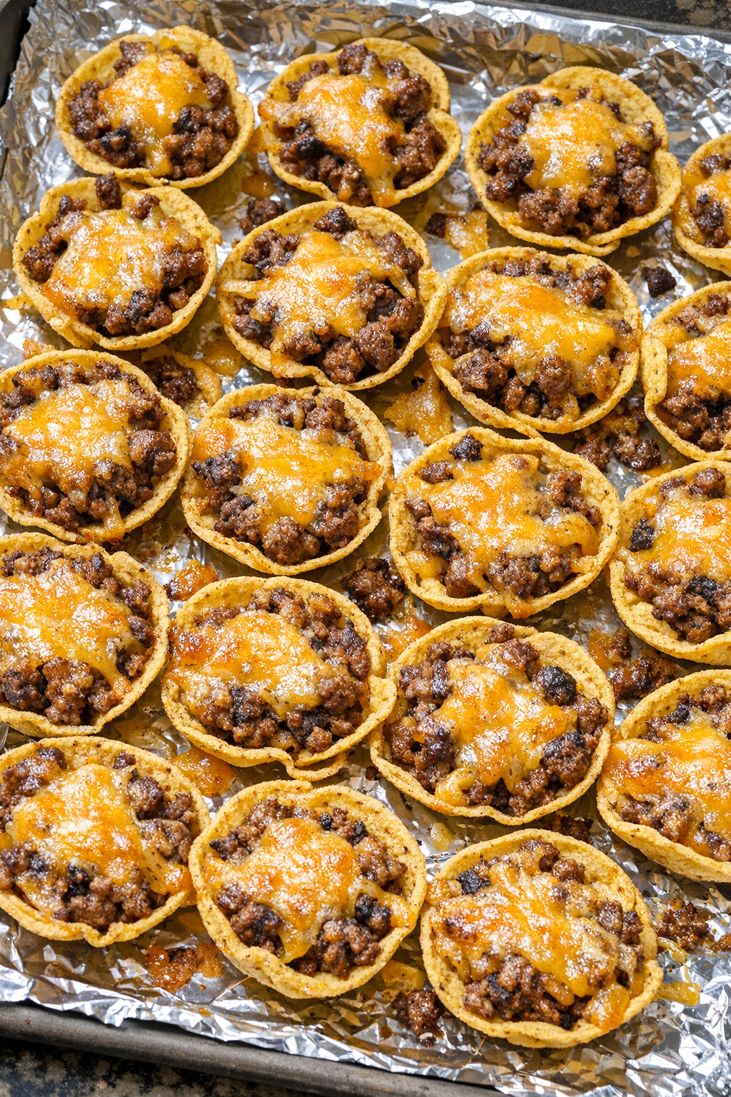 Oven baked beef corn chip scoops on a foil-lined baking sheet