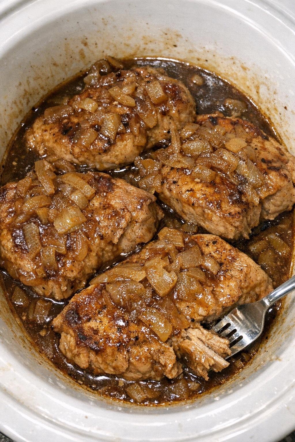 Slow cooker Worcestershire onion pork chops in a white slow cooker