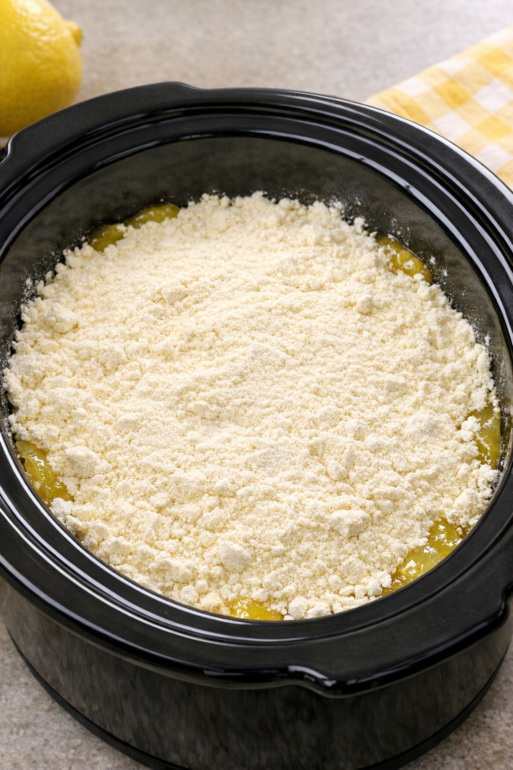 Dry lemon cake mix layered over lemon filling in the slow cooker