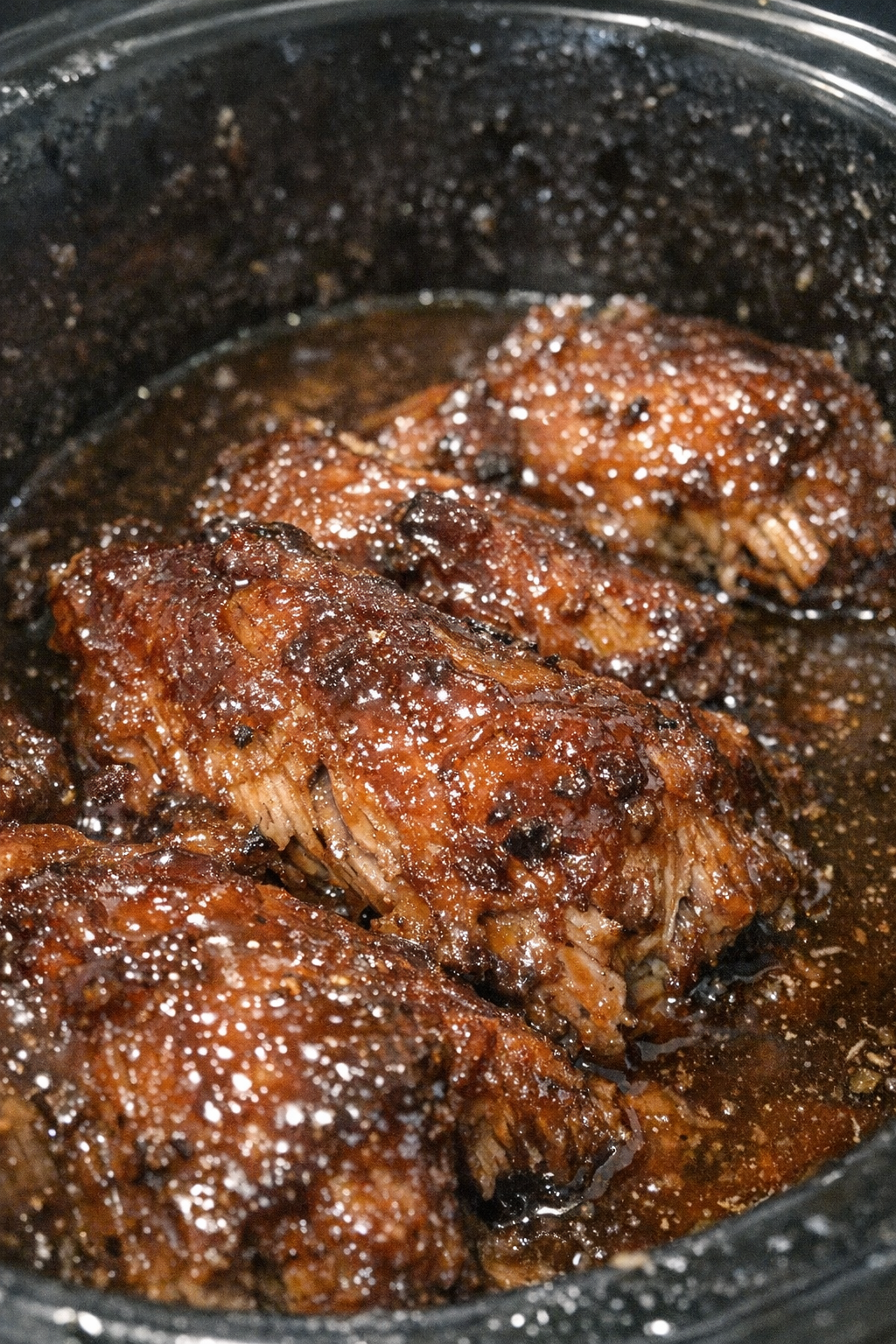 Glossy roasted protein in dark amber sauce in a slow cooker