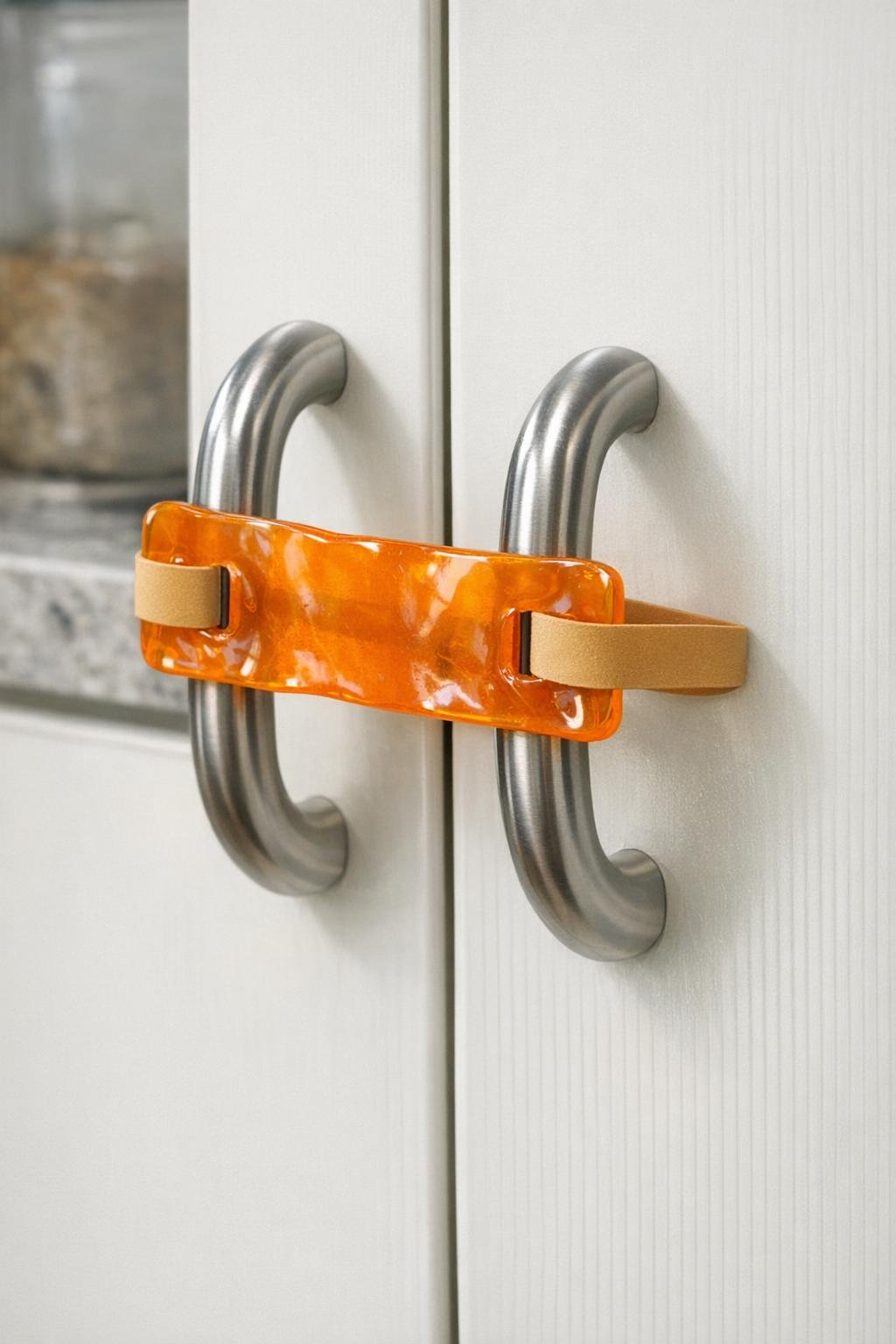 Finished latch made from remelted orange pill-bottle plastic installed on cabinet handles