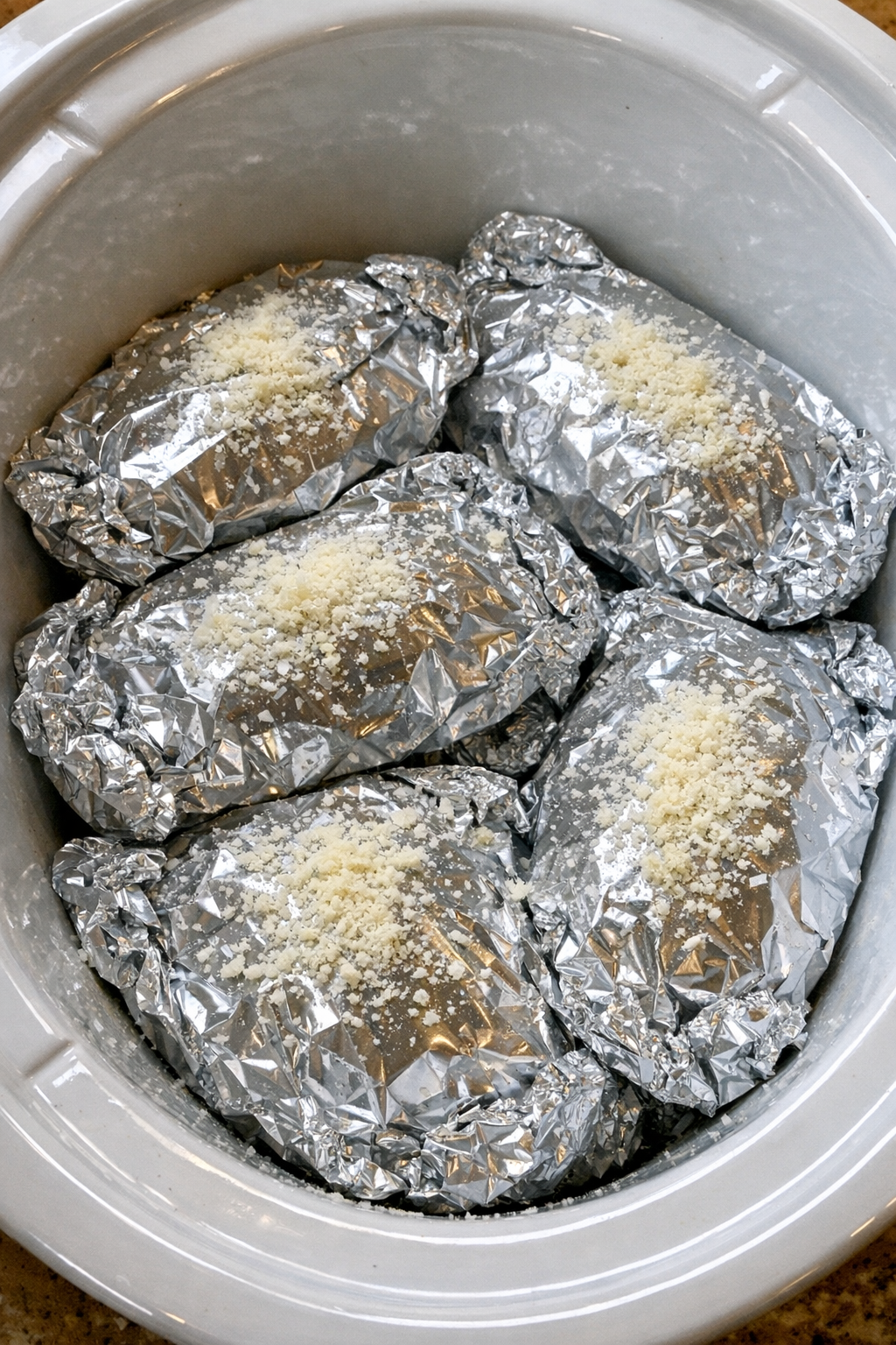 Slow cooker creamy Tuscan chicken pasta foil packets in a white slow cooker