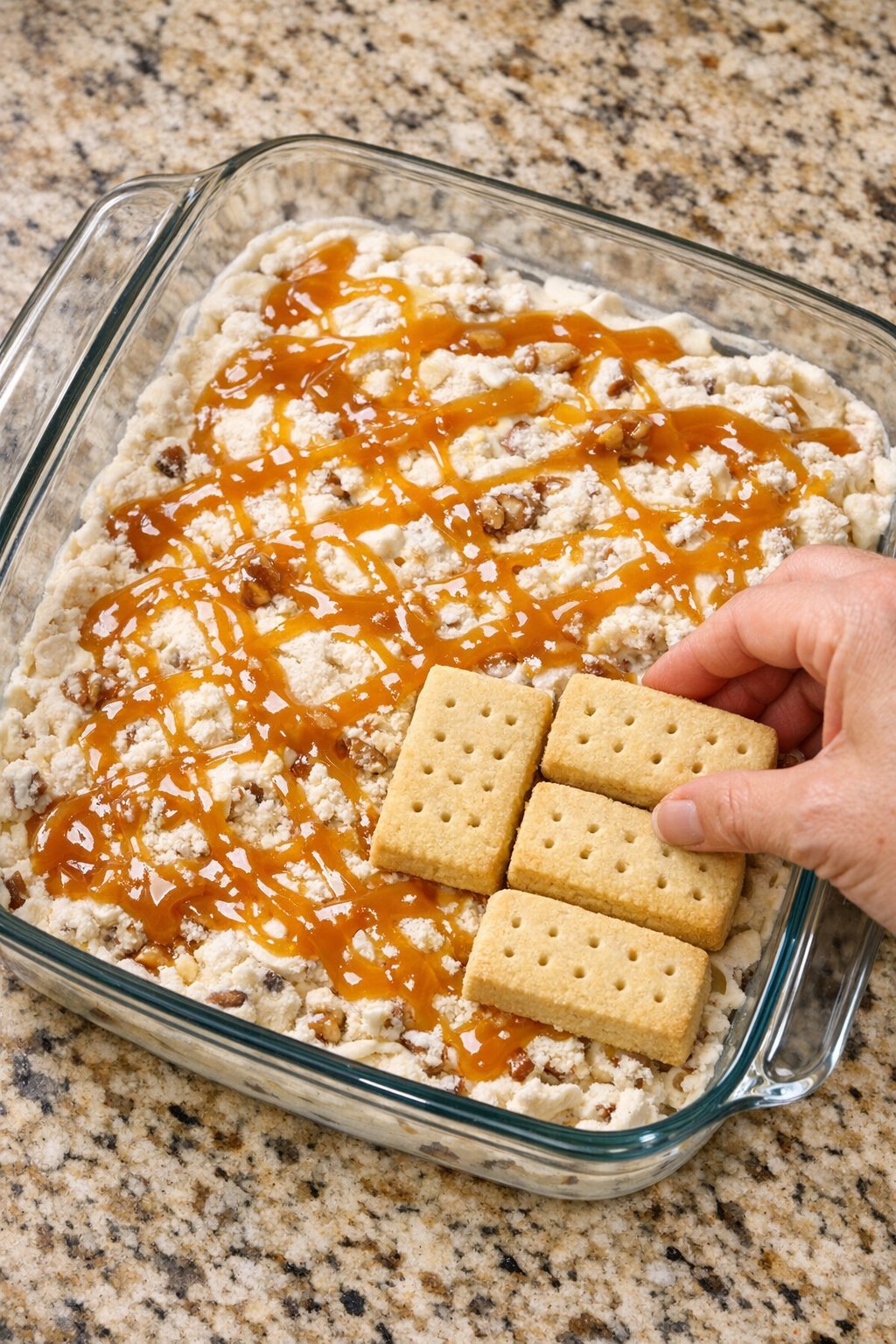 Caramel drizzled over ice cream with a second cookie layer ready