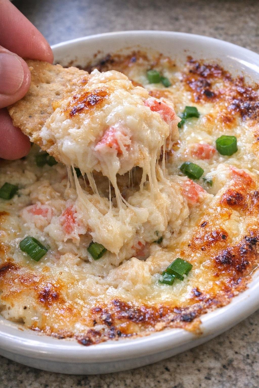 Bubbling golden-brown cheesy crab dip on a white plate