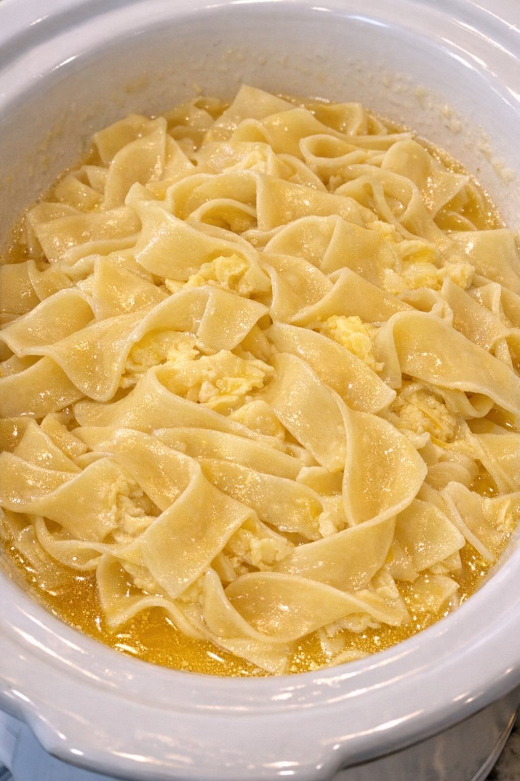 Slow cooker Amish egg butter noodles in a white slow cooker