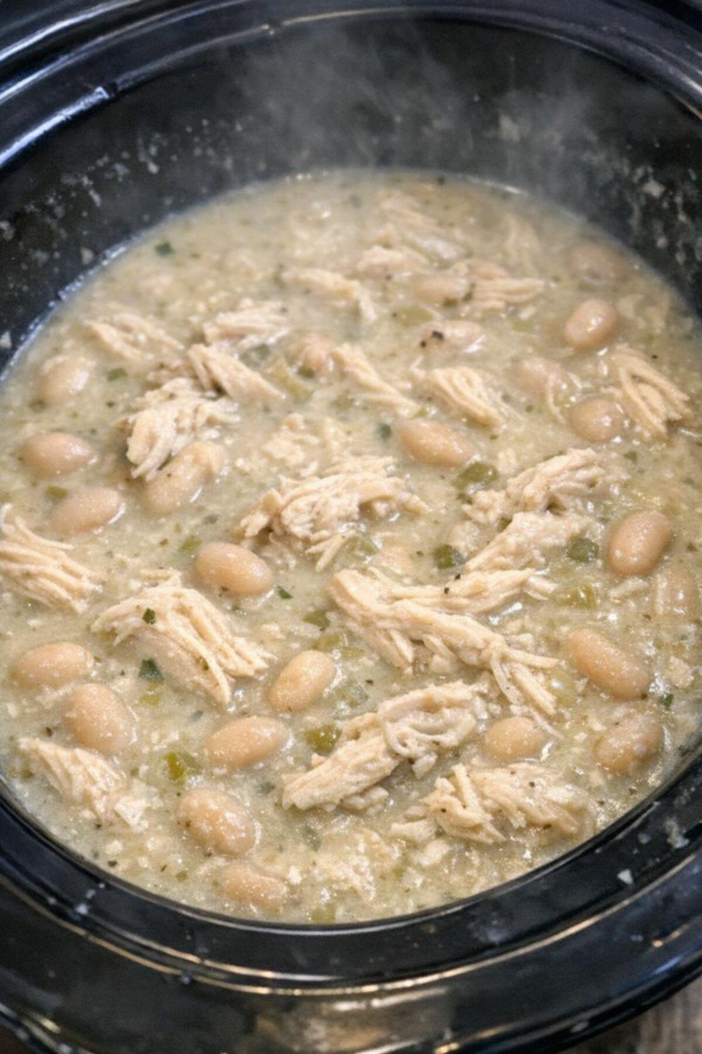 Creamy white chicken chili in a black slow cooker crock
