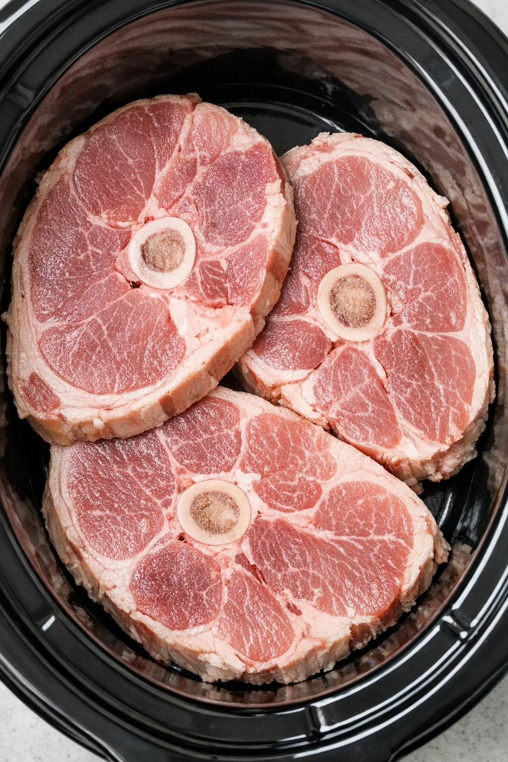 Ham steaks arranged in the bottom of a slow cooker