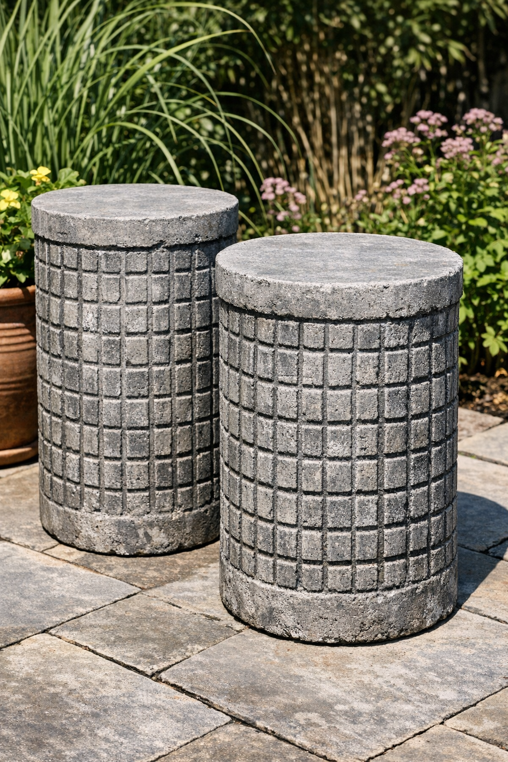 Two finished wire-textured cement garden pedestals outdoors